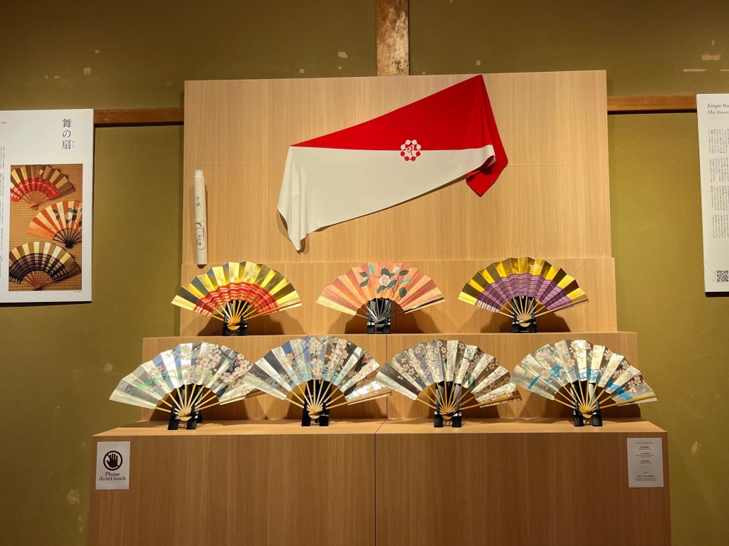 祇園花街藝術資料館展示的舞扇與家徽旗幟，扇面圖案多樣繽紛，是舞妓京舞表演的重要道具。