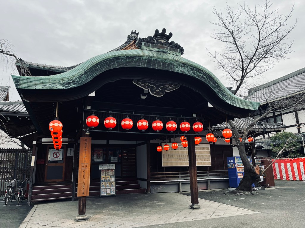 京都祇園甲部歌舞練場正門，唐破風屋頂下掛滿紅色團子家紋提燈，是舞妓與藝妓表演練習與演出的重要場所。